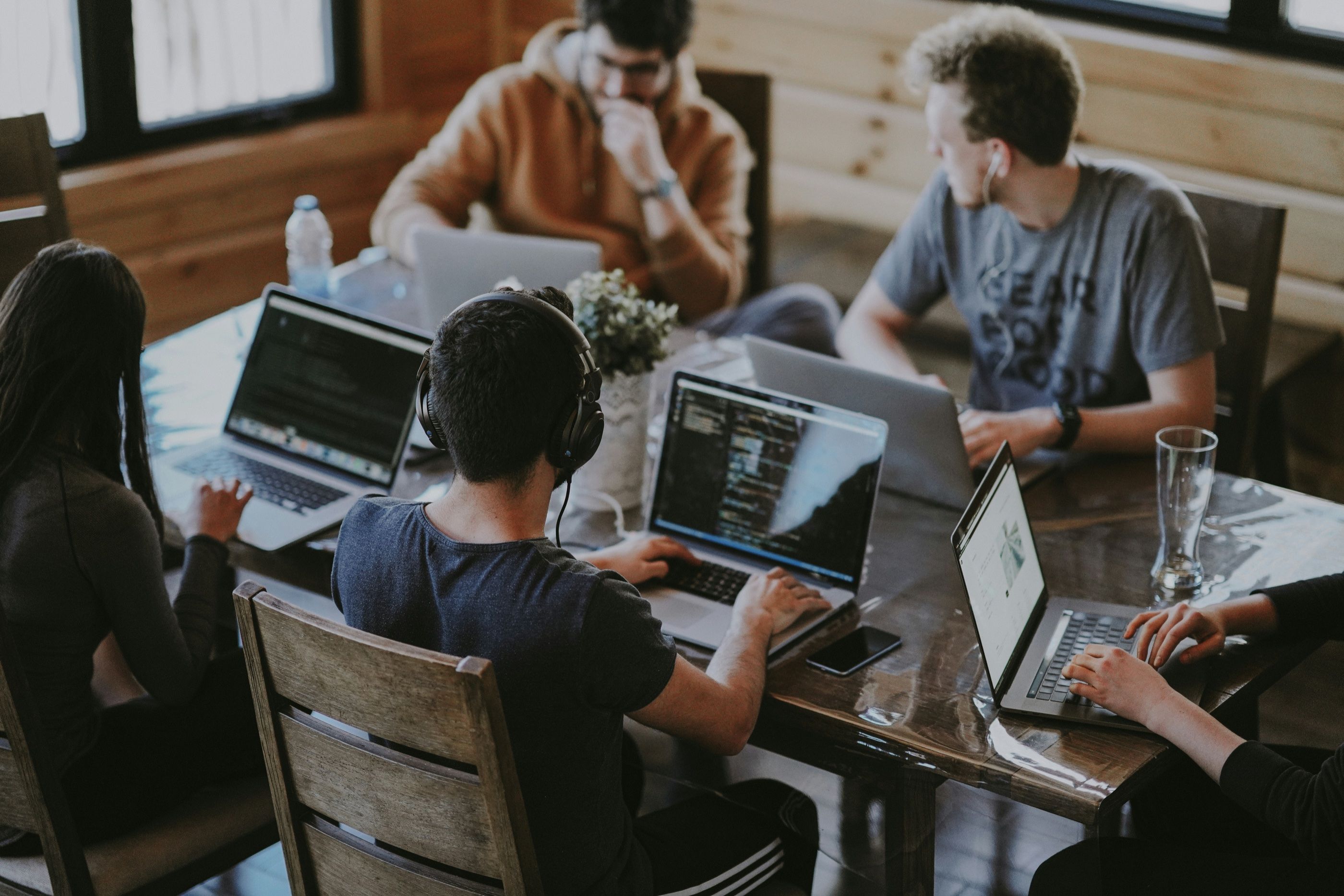 Equipo trabajando con computadoras portátiles alrededor de una mesa
