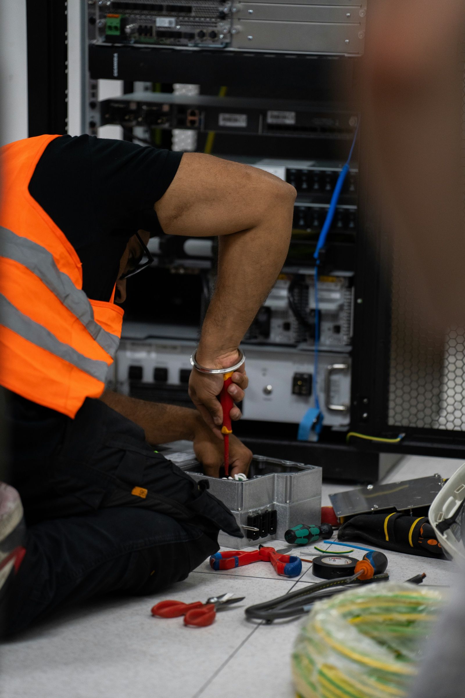 Técnico trabajando con herramientas frente a un rack de equipos de red